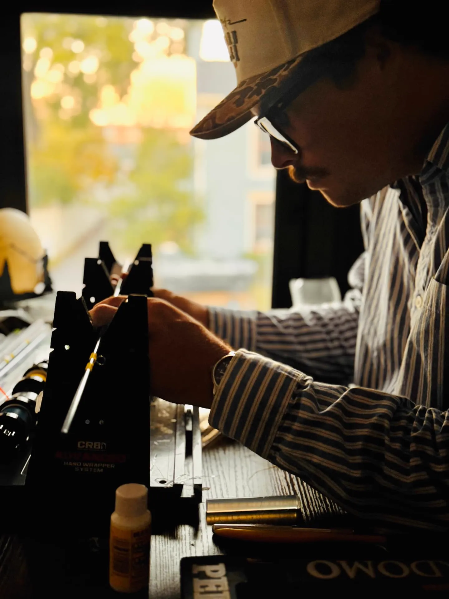 Mitchell Smith wrapping a fly rod guide at his bench by the shop window in Franklin, Tennessee