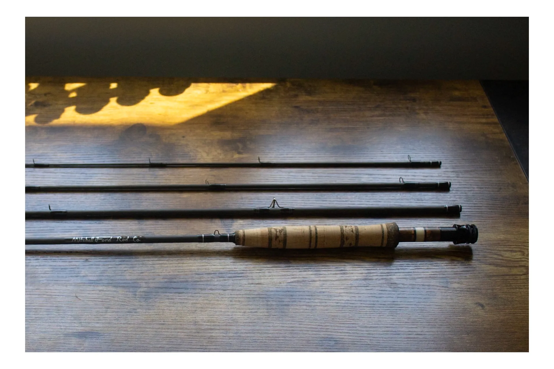 Complete fly rod with all sections displayed on rustic wood